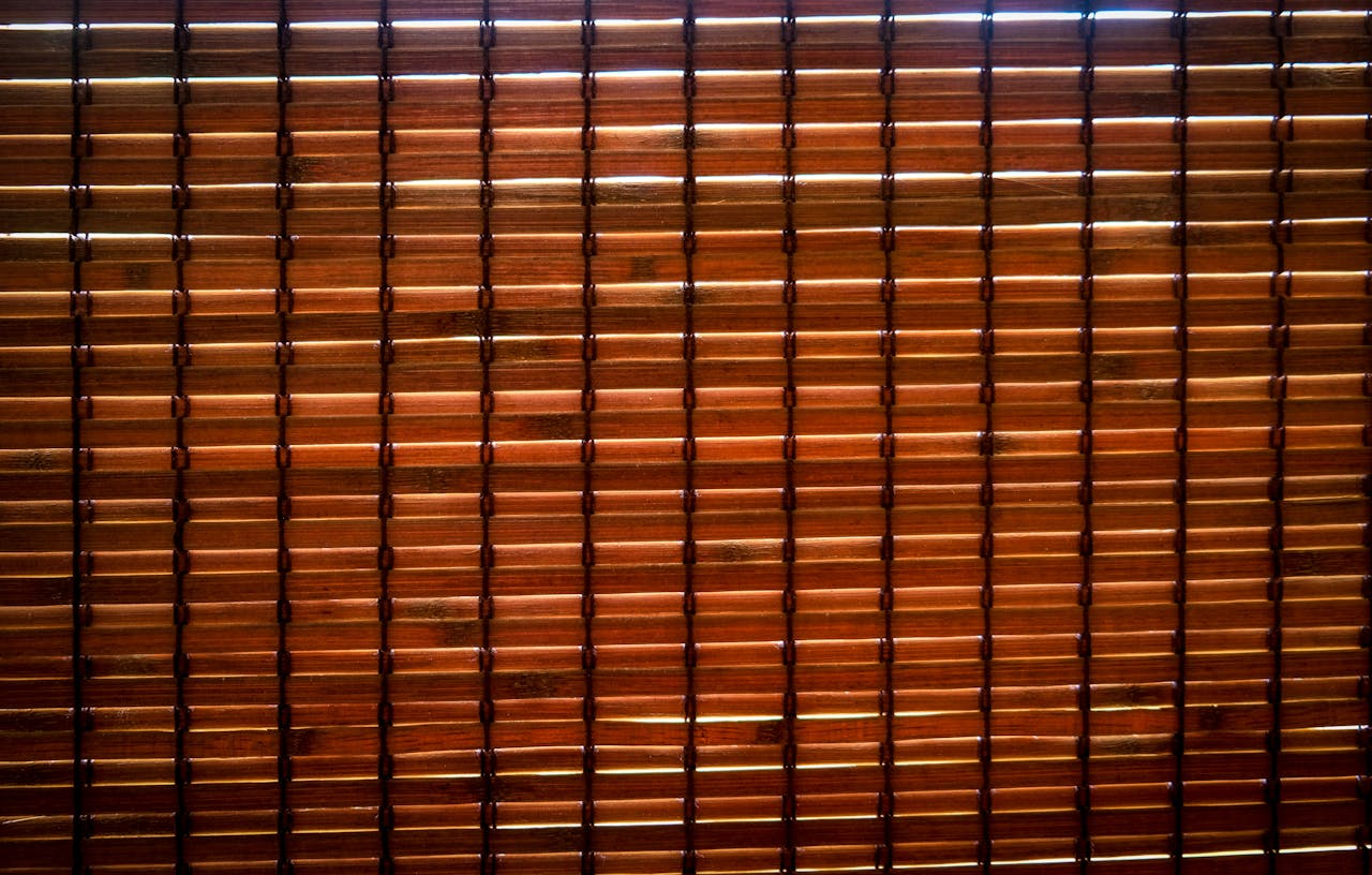 Detailed image of brown bamboo blinds with light filtering through, creating patterns.